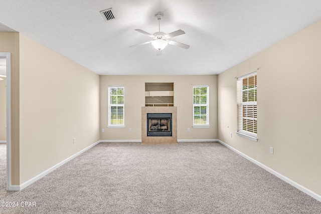 unfurnished living room featuring carpet flooring, a tiled fireplace, and ceiling fan