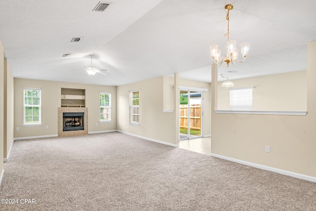 unfurnished living room with a healthy amount of sunlight, a tile fireplace, and light colored carpet