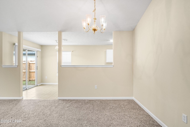 empty room with a notable chandelier and light colored carpet