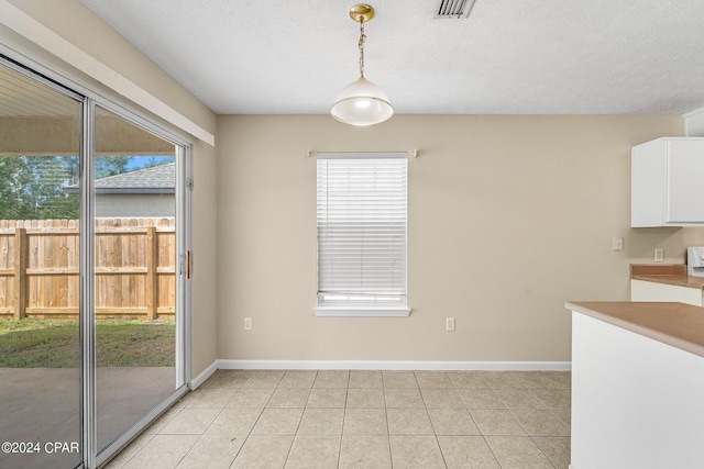 unfurnished dining area with a textured ceiling and light tile patterned floors