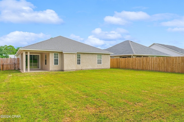 rear view of property with a patio and a lawn