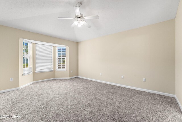 spare room featuring a textured ceiling, carpet flooring, lofted ceiling, and ceiling fan