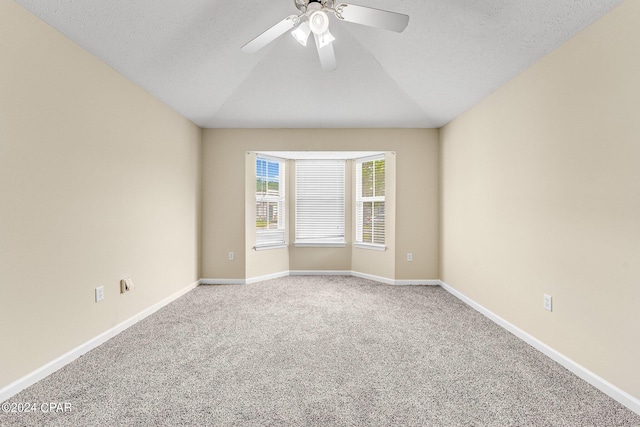 carpeted empty room with a textured ceiling, ceiling fan, and lofted ceiling