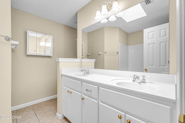 bathroom featuring a skylight, tile patterned flooring, and double vanity