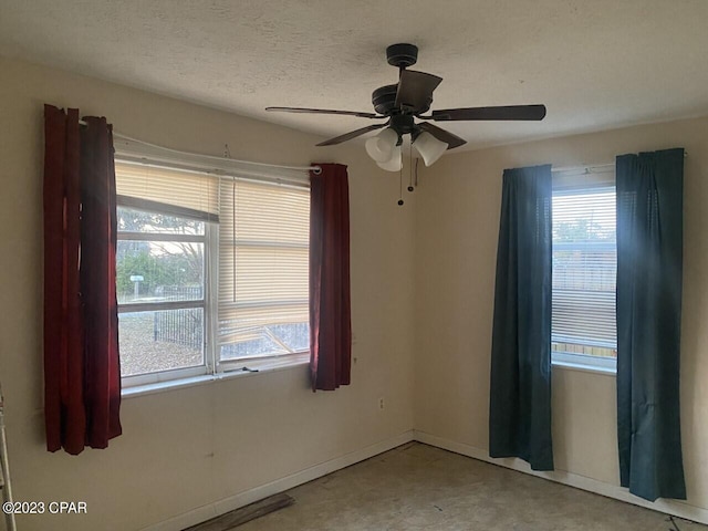 empty room with ceiling fan and a textured ceiling