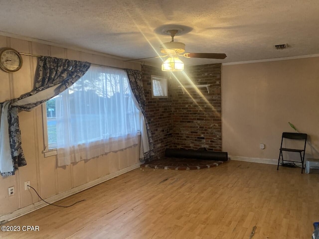 unfurnished living room with hardwood / wood-style floors, ornamental molding, a textured ceiling, and ceiling fan