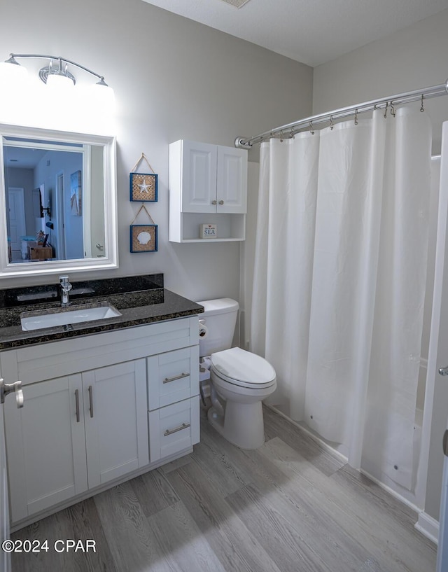 bathroom featuring hardwood / wood-style flooring, vanity, toilet, and walk in shower