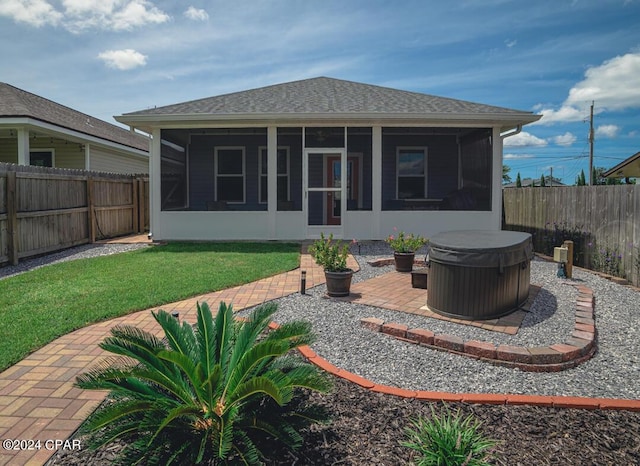 rear view of house with a hot tub, a patio, a sunroom, and a yard