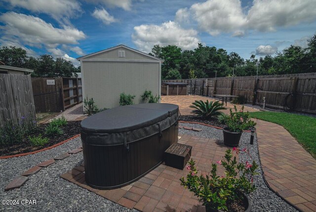 view of patio / terrace featuring a hot tub and a storage shed