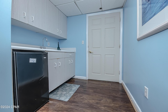 kitchen with black fridge, sink, a drop ceiling, and dark hardwood / wood-style flooring