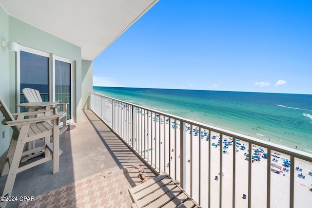 balcony with a water view and a view of the beach