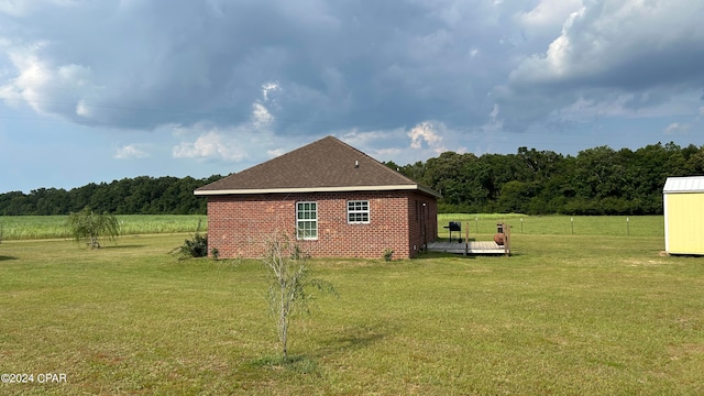 view of side of home with a yard and a storage unit