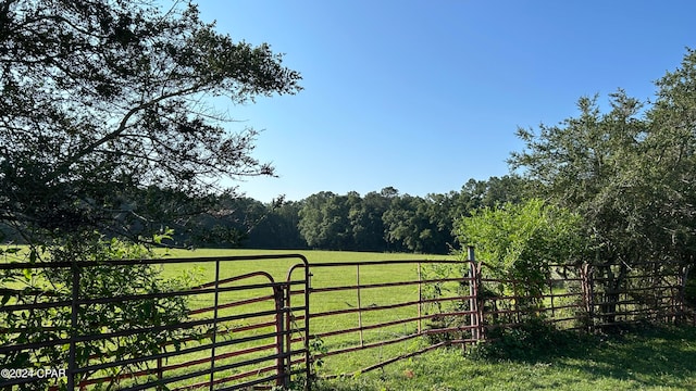 view of gate featuring a rural view and a lawn