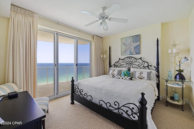 carpeted bedroom featuring a water view, access to outside, ceiling fan, and a textured ceiling