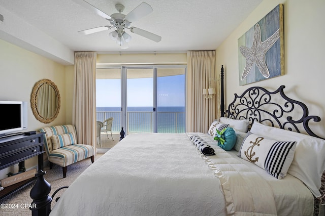 bedroom with carpet floors, a water view, ceiling fan, a textured ceiling, and access to outside