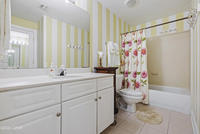 bathroom with visible vents, toilet, a textured ceiling, tile patterned flooring, and wallpapered walls