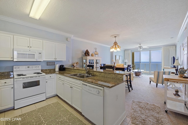 kitchen featuring white appliances, white cabinets, ornamental molding, a peninsula, and a sink