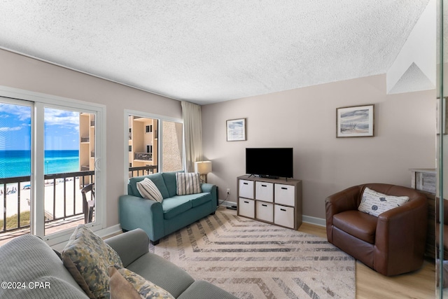 living room with a textured ceiling, light hardwood / wood-style floors, and a water view