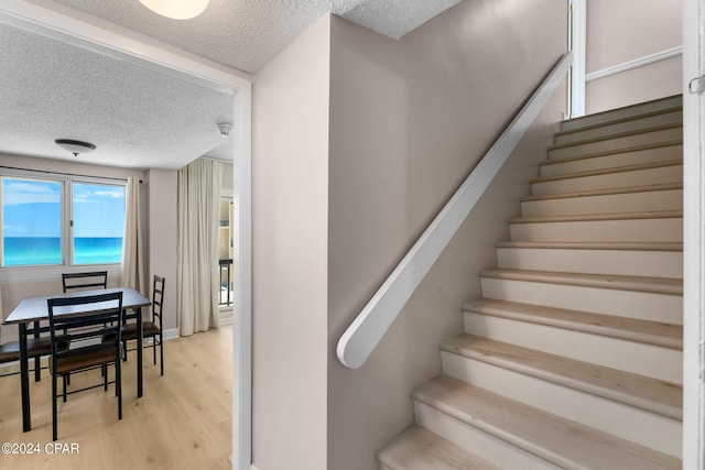 stairway with wood-type flooring and a textured ceiling