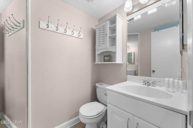 bathroom featuring toilet, a textured ceiling, and vanity