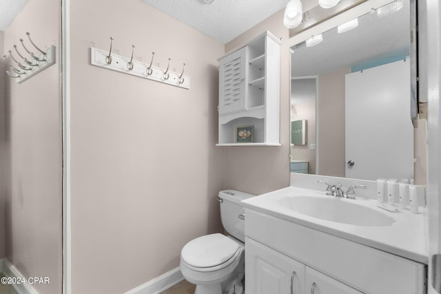 bathroom with a textured ceiling, toilet, and vanity