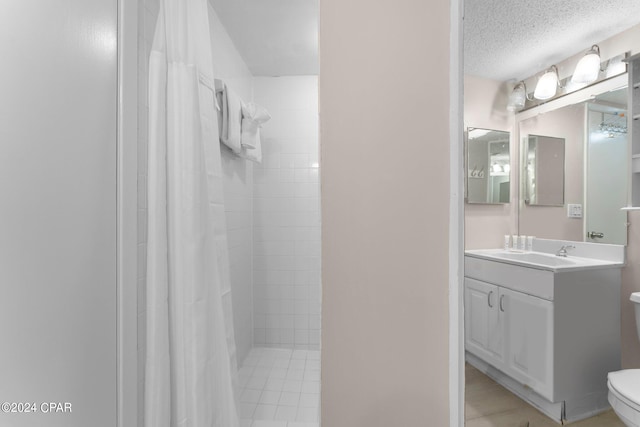 bathroom featuring tile patterned flooring, toilet, a textured ceiling, and vanity