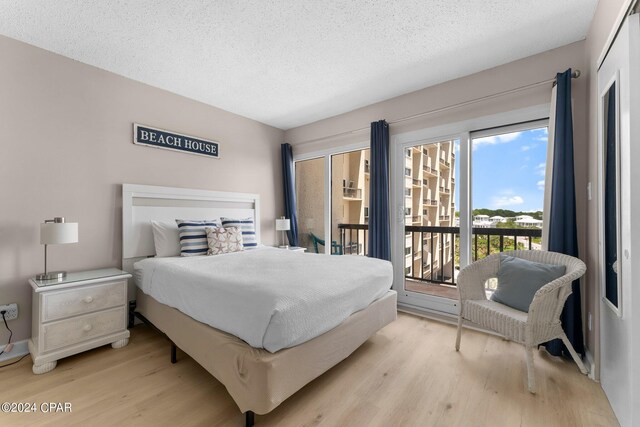 bedroom featuring a textured ceiling, light hardwood / wood-style floors, multiple windows, and access to outside