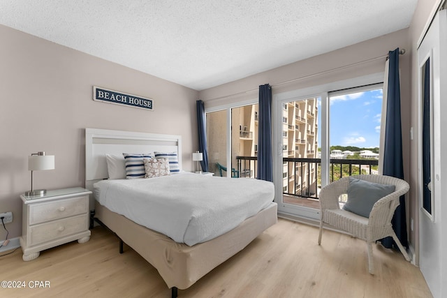 bedroom with light wood-type flooring, access to exterior, and a textured ceiling