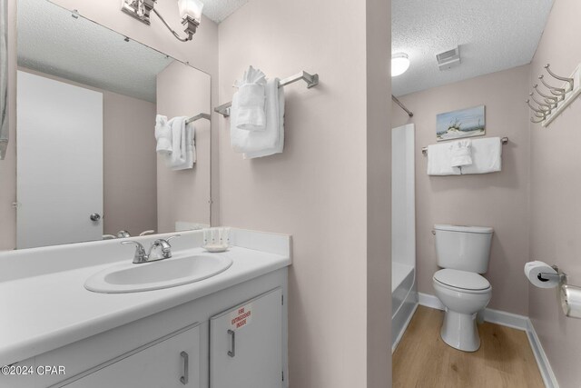 full bathroom with toilet, shower / bathtub combination, vanity, hardwood / wood-style floors, and a textured ceiling