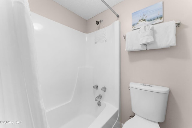 bathroom featuring a textured ceiling, toilet, and bathtub / shower combination