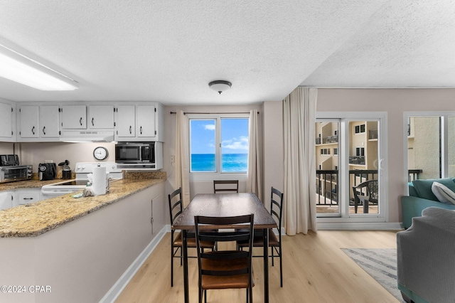 interior space with light hardwood / wood-style floors, light stone counters, white electric range oven, a textured ceiling, and white cabinets