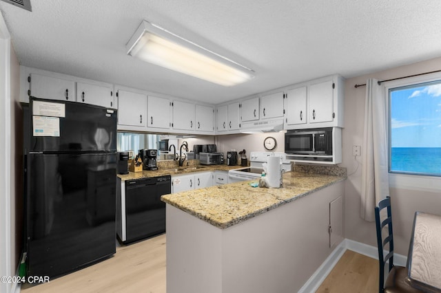 kitchen featuring light hardwood / wood-style floors, white cabinets, black appliances, and light stone countertops