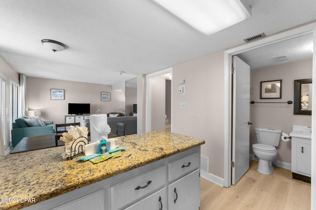 kitchen featuring light hardwood / wood-style flooring, light stone counters, and a textured ceiling