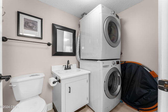 washroom with sink, a textured ceiling, and stacked washing maching and dryer