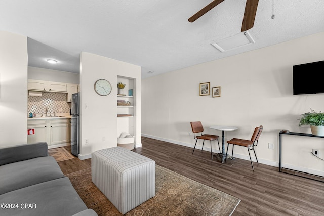 living room with ceiling fan, sink, dark hardwood / wood-style flooring, and a textured ceiling