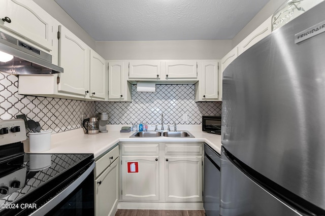 kitchen featuring stainless steel appliances, white cabinetry, backsplash, hardwood / wood-style flooring, and sink