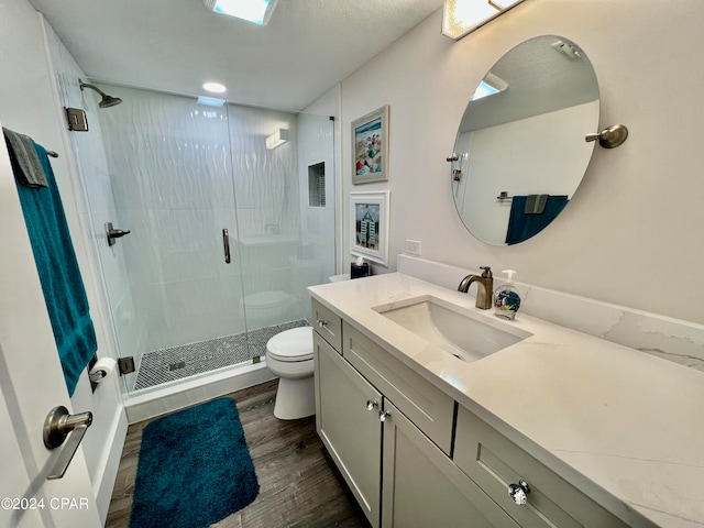 bathroom featuring a shower with shower door, toilet, vanity, and hardwood / wood-style flooring