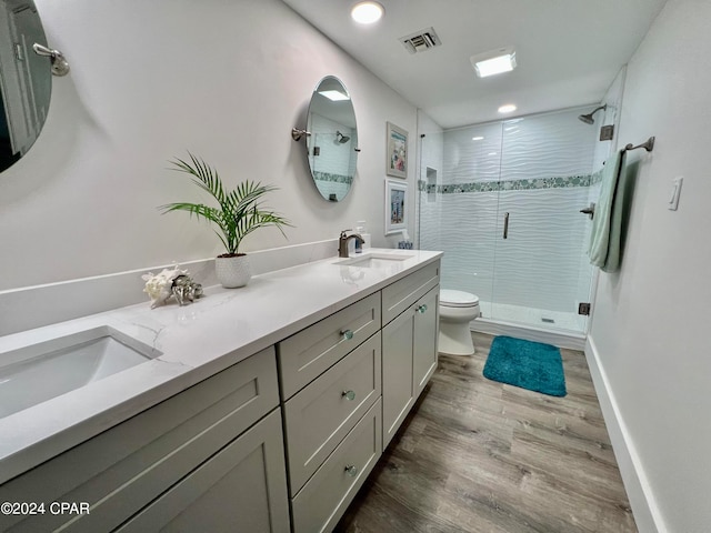 bathroom featuring toilet, hardwood / wood-style floors, double vanity, and walk in shower