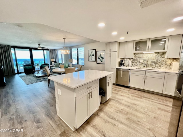 kitchen with light wood-type flooring, tasteful backsplash, hanging light fixtures, dishwasher, and a center island