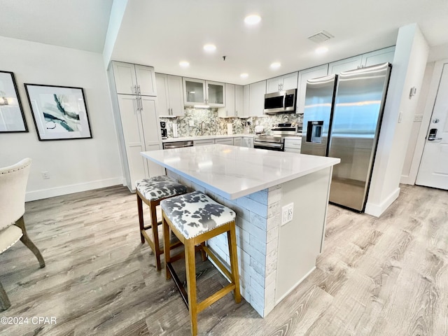 kitchen featuring tasteful backsplash, light hardwood / wood-style floors, sink, a center island, and stainless steel appliances