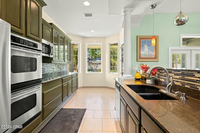 kitchen with appliances with stainless steel finishes, tasteful backsplash, dark stone countertops, and sink