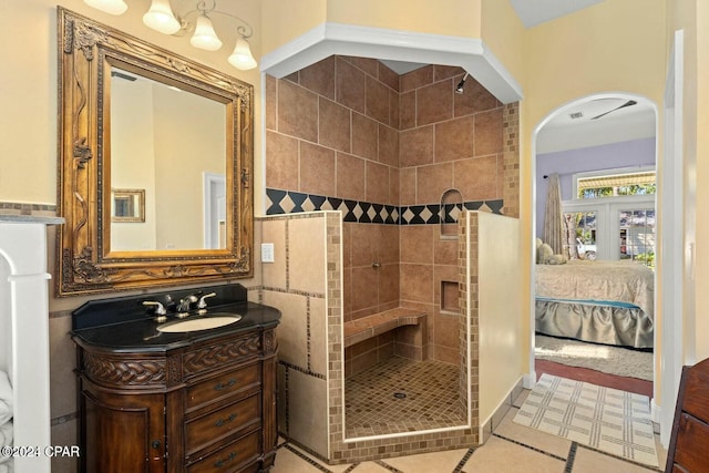 bathroom featuring french doors, tile patterned flooring, tiled shower, vanity, and tile walls