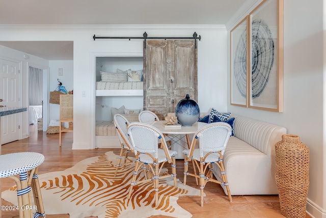 dining room featuring hardwood / wood-style floors, a barn door, and crown molding