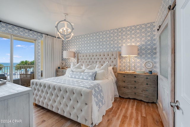 bedroom with an inviting chandelier, light hardwood / wood-style flooring, access to exterior, and a water view