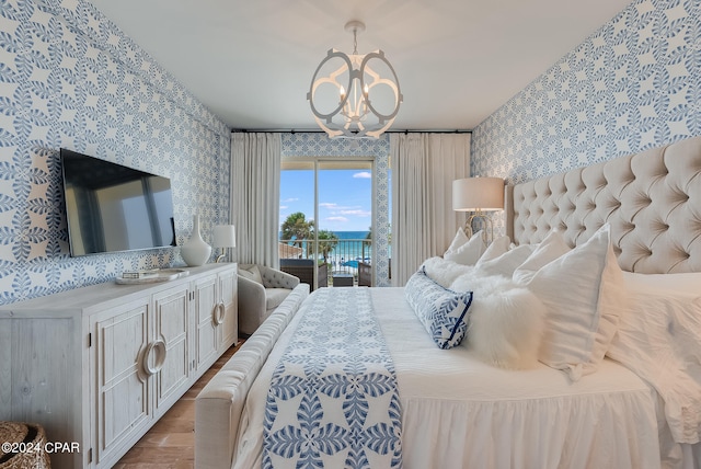 bedroom featuring access to outside, hardwood / wood-style flooring, and a chandelier