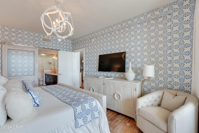 bedroom with light wood-type flooring, connected bathroom, and a chandelier