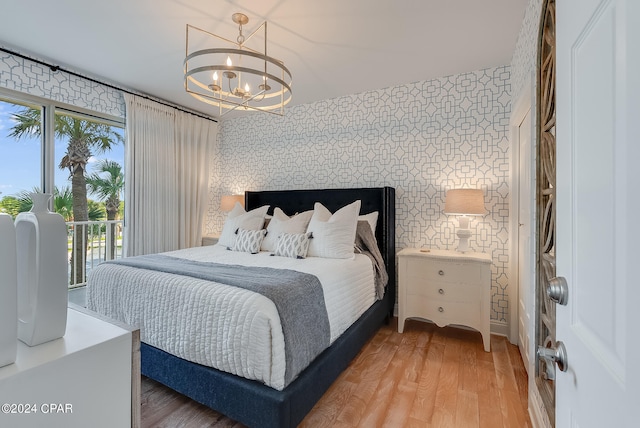 bedroom featuring light hardwood / wood-style floors, access to exterior, and a chandelier