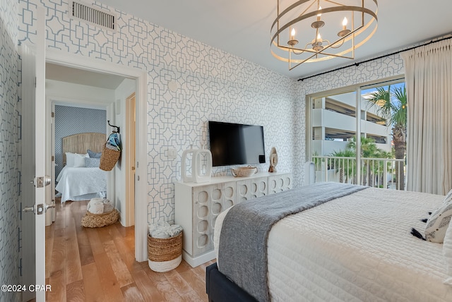 bedroom with access to exterior, light hardwood / wood-style floors, and a chandelier