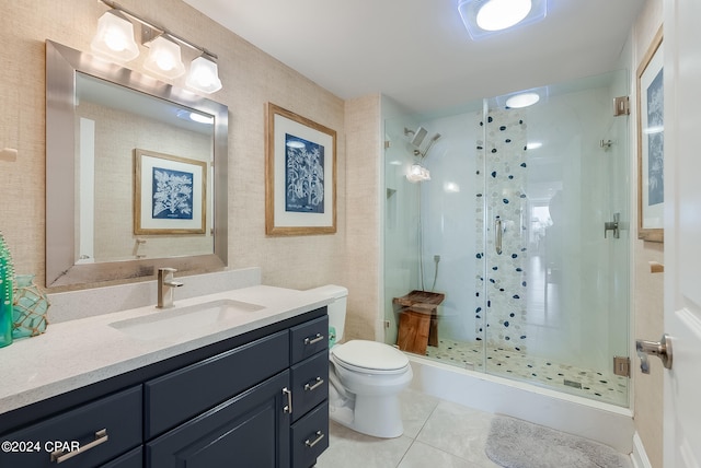 bathroom featuring tile patterned flooring, toilet, vanity, and a shower with shower door