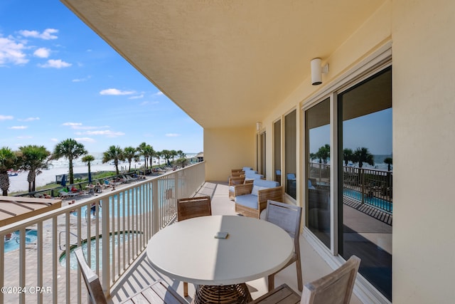 balcony featuring a water view and a fenced in pool